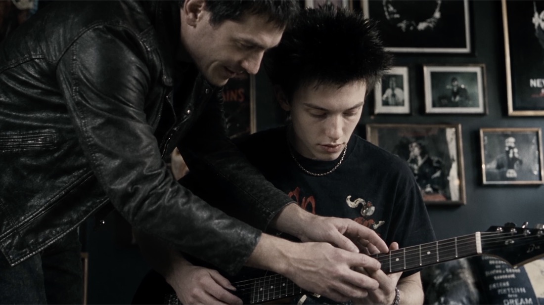 An older man teaching Gabriel guitar