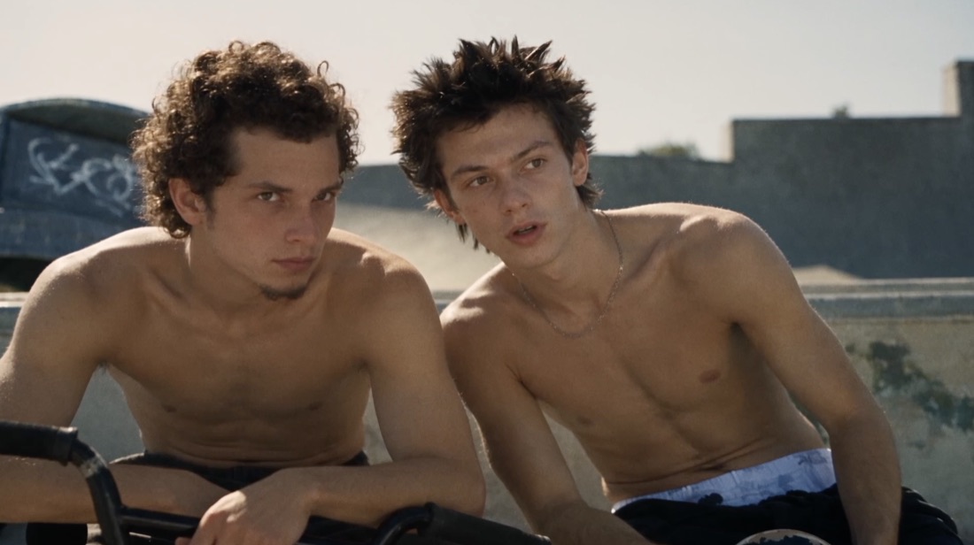 Two shirtless skaters in the sun