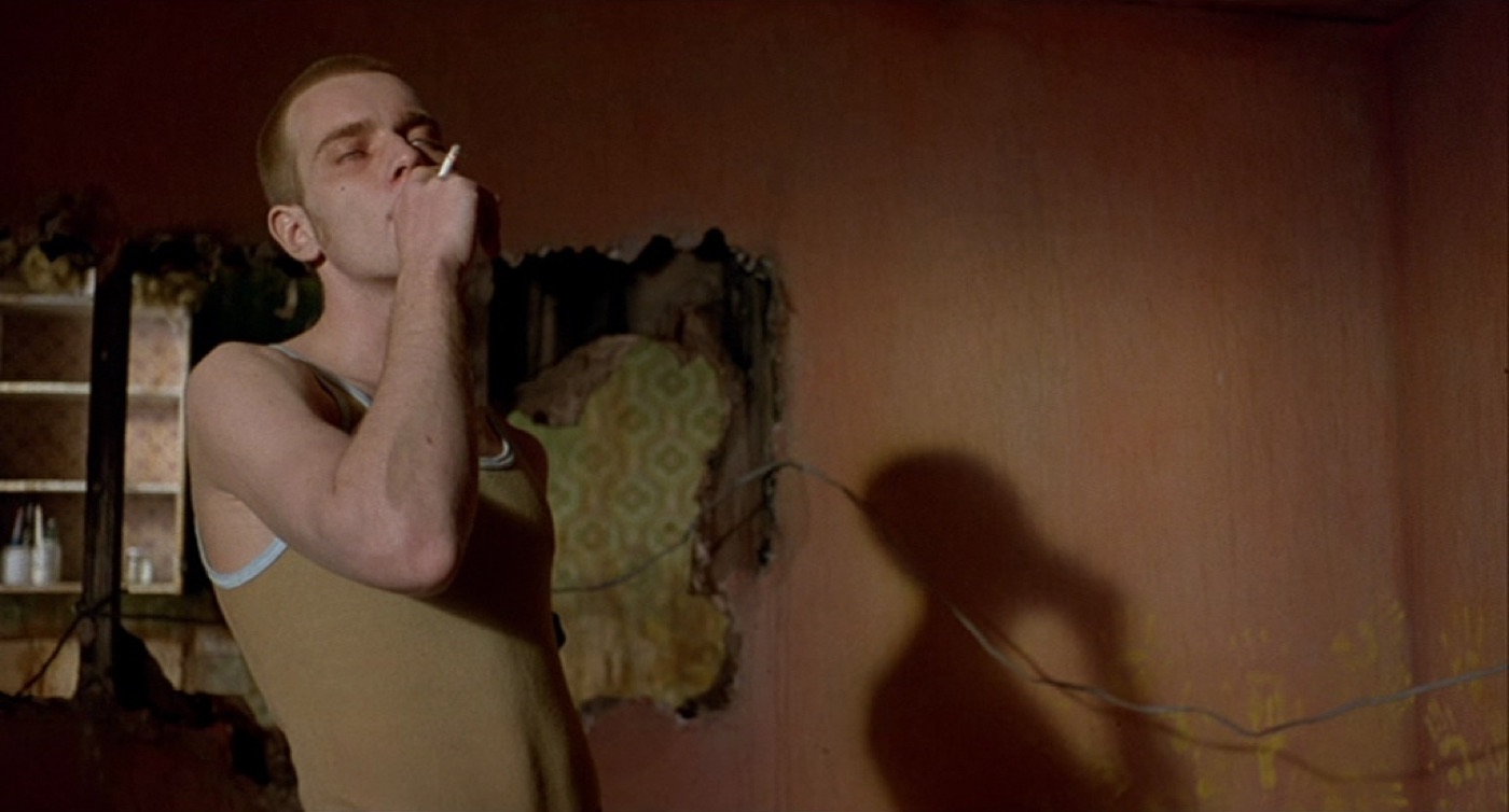 Trainspotting (1996): a young man smoking in a warm-lit room